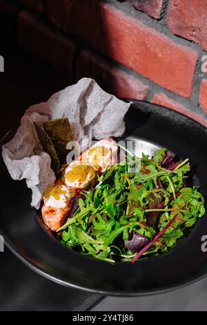 Deliziosa insalata di gamberi servita con verdure miste fresche e un condimento saporito su un piatto nero Foto Stock