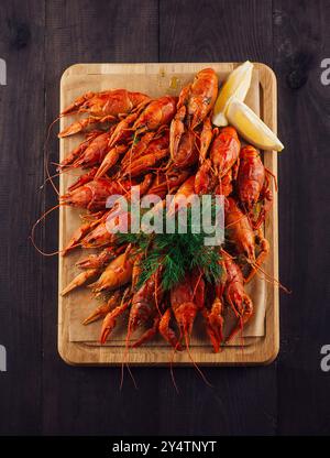 Aragosta bollita decorata con fette di aneto e limone adagiate sulla tavola di legno Foto Stock