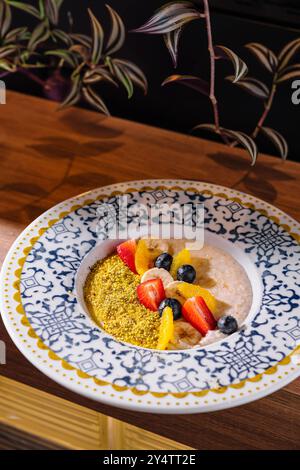 Porridge di farina d'avena ricoperto di frutta tritata come fragole, mirtilli e fette di banana con pistacchi schiacciati Foto Stock