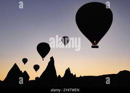 Silhouette di mongolfiere volanti e paesaggi rocciosi all'alba a Goreme, Cappadocia, Turchia, Asia Foto Stock