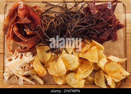 Vista dall'alto di un assortimento di spuntini salati per la birra sdraiati su una tavola di legno Foto Stock