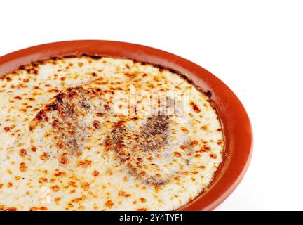 Deliziose lasagne con cottura di carne e formaggio in un piatto rustico di argilla, isolato su sfondo bianco Foto Stock