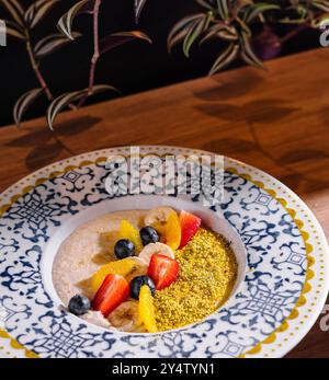 Porridge di farina d'avena ricoperto di frutta tritata come fragole, mirtilli e fette di banana con pistacchi schiacciati Foto Stock