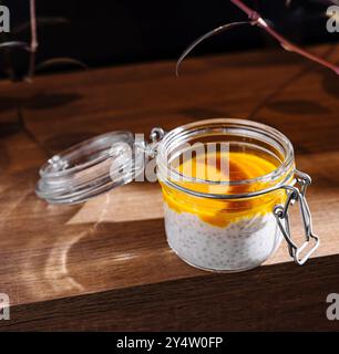 Colazione deliziosa e salutare con semi di chia e mango in barattolo viene servita su un tavolo di legno Foto Stock