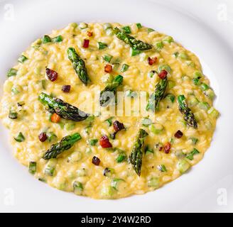 Risotto cremoso con asparagi e pancetta serviti su un piatto bianco Foto Stock