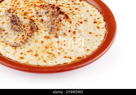 Deliziose lasagne con cottura di carne e formaggio in un piatto rustico di argilla, isolato su sfondo bianco Foto Stock