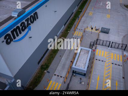 Dummerstorf, Germania. 19 settembre 2024. Una strada di accesso chiusa al nuovo centro logistico del rivenditore online Amazon. (Girato con un drone) circa 1.000 dipendenti devono lavorare nel grande magazzino dopo la fase di avvio. Inizialmente, è prevista un'operazione parziale con circa 450 dipendenti fino alla fine dell'anno. Nessuna merce deve essere inviata direttamente ai clienti da Dummerstorf. Il nuovo centro logistico verrà utilizzato per immagazzinare articoli relativamente grandi, come gli attrezzi da giardino, in scaffali alti e per la consegna. Crediti: Jens Büttner/dpa/Alamy Live News Foto Stock