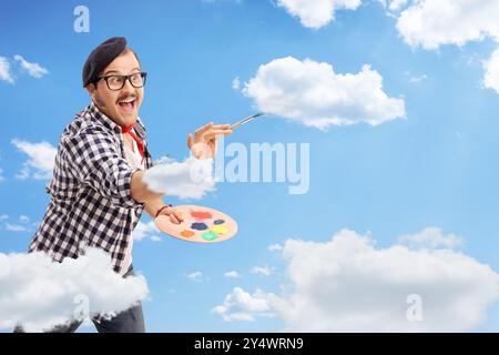 Artista maschile eccitato che dipinge nuvole nel cielo Foto Stock