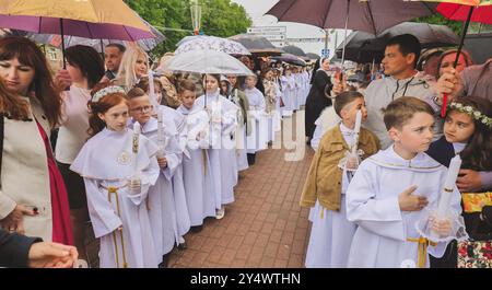 Lida, Bielorussia - 15 giugno 2021: I bambini con i genitori in possesso di candele celebrano la prima cerimonia di Santa comunione Foto Stock