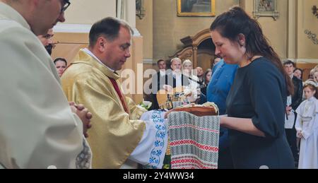 Lida, Bielorussia - 15 giugno 2021: Sacerdote che benedice il pane tenuto da una donna in chiesa durante la cerimonia Foto Stock