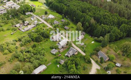 Vista aerea di un piccolo villaggio con tradizionali case in legno, circondato da lussureggianti foreste verdi e da un fiume tortuoso Foto Stock