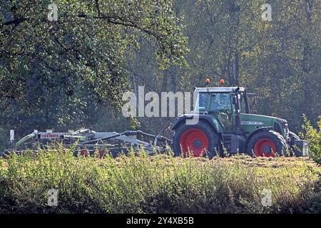 Landarbeit in Nordrhein-Westfalen Ein Schlepper des Herstellers Fendt befährt mit einem Heuwender eine Auenlandschaft um eine gleichmäßige Trocknung von dem Heu zu erzielen. Essen Nordrhein-Westfalen Deutschland *** lavori agricoli in Renania settentrionale-Vestfalia Un trattore del produttore Fendt guida un fieno tedder attraverso un paesaggio prato per ottenere un'essiccazione uniforme del fieno Essen Renania settentrionale-Vestfalia Germania Foto Stock