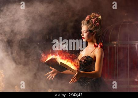 Donna strega in abito nero vintage con libro di incantesimi nel vecchio castello. Halloween. Festeggiamenti. Concetto di stregoneria, atmosfera mistica da favola. Evocare incantesimi magici. Foto Stock