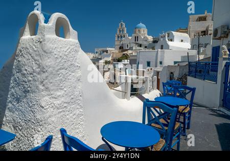 Strade strette e tortuose, case bianche, tavoli e sedie blu, un campanile e una chiesa. Splendida cittadina di Megalochori, Santorini, Foto Stock