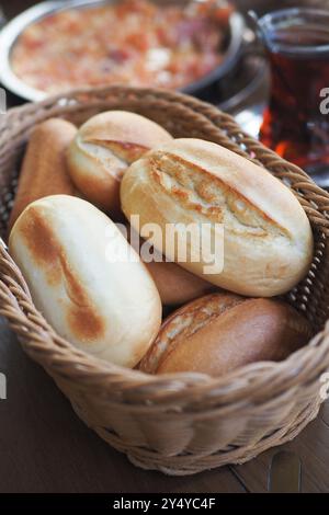 Deliziosi panini appena sfornati serviti in un cestino accompagnato da tè Foto Stock