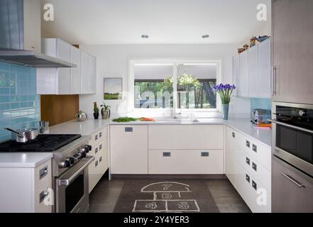 Moderna cucina bianca con piastrelle d'acqua in una casa ristrutturata di metà secolo Foto Stock