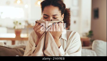 Donna, bucato o odorare i vestiti in casa per un profumo fresco, biancheria pulita o fragranze di tessuto sul divano. Servizio di pulizia, persona o aroma delle pulizie primaverili Foto Stock