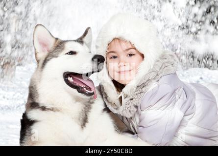 La bambina abbraccia un cucciolo malamuto di cinque mesi Foto Stock