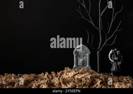 Sfondo di Halloween con lapide che hanno albero nero e fantasma sfocato con erba secca su sfondo nero. Concetto minimale. Foto Stock