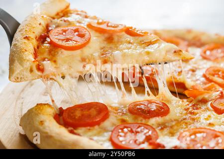 tagliate una fetta di pizza. il formaggio fuso si allunga dal pezzo Foto Stock