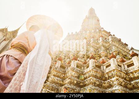 Bangkok, Thailandia - 11 febbraio 2024: Giovani coppie thailandesi indossano abiti tradizionali per una sessione fotografica al Wat Arun bellissimo tempio buddista sul sole caldo Foto Stock