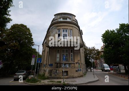 Architettura storica caratterizzata da un unico edificio ad angolo con graffiti in un ambiente urbano durante una giornata nuvolosa Foto Stock