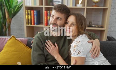 Una coppia amorevole abbraccia calorosamente nel loro accogliente soggiorno, riflettendo un rapporto confortevole e affettuoso. Foto Stock