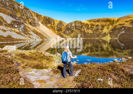 Un camminatore presso lo splendido specchio d'acqua chiamato Loch Brandy, un lago di montagna a Glen Clova, Angus, Scozia Foto Stock