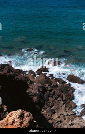 Le onde oceaniche si schiantano contro la costa rocciosa. Foto Stock