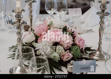 Elegante centro matrimoni con rose rosa e portacandele argento. Foto Stock