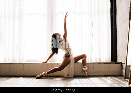 Ballerino in una posa divisa, che raggiunge la luce Foto Stock