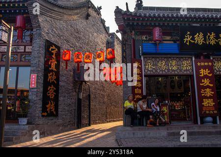 Vicolo a Ping Yao, Shanxi, Cina. Il sole che tramonta illumina le lanterne rosse. Foto Stock