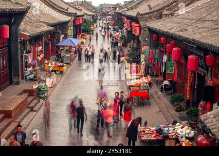 Strada trafficata a Ping Yao, Shanxi, Cina. Con lanterne rosse tradizionali e persone in movimento. Foto Stock