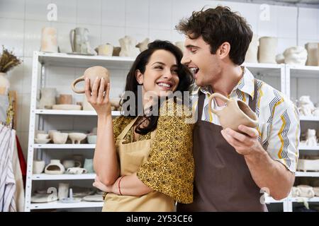 Una coppia crea ceramiche insieme, condividendo sorrisi e creatività nello studio. Foto Stock