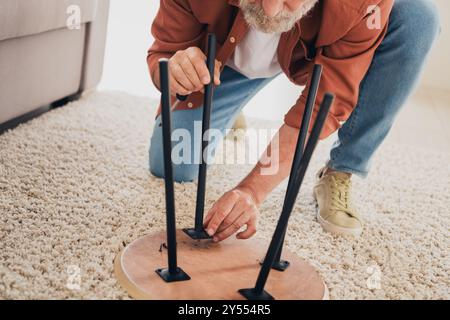 Foto ritagliata della sedia di riparazione maschile senior vestito di casa marrone accogliente salotto interno della casa con luce diurna Foto Stock