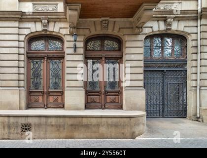L'edificio storico presenta porte in legno splendidamente lavorate con disegni ornati e un cancello in ferro battuto dettagliato. Le classiche caratteristiche architettoniche aggiungono fascino al paesaggio urbano. Foto Stock