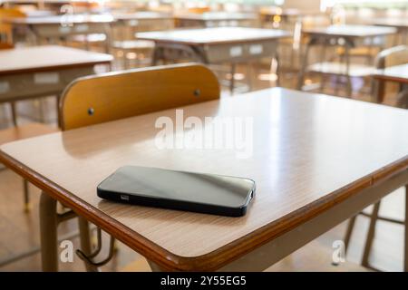 Uno smartphone su una scrivania in un'aula di proprietà e utilizzata da uno studente Foto Stock