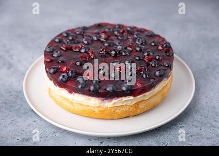 Torta tirolese con crema pasticcera morbida, ciliegie e mirtilli. Torta di biscotti con panna leggera, con frutti di bosco freschi e gelatina. Cottura tradizionale. Primo piano, se Foto Stock