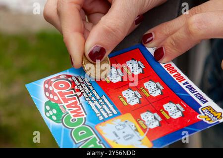 Napoli, Italia - 25 aprile 2011: Dado Matto, gioco del monopolio statale italiano chiamato Gratta e Vinci. La donna gratta il biglietto della lotteria sperando di vincere. Foto Stock