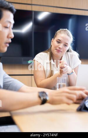 In ufficio, colleghi multirazziali che collaborano in un ufficio moderno con un notebook Foto Stock