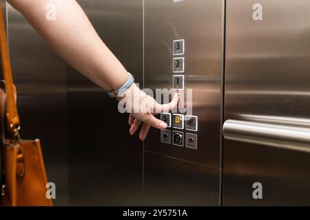 Premendo il pulsante dell'ascensore, la persona con la borsa utilizza l'ascensore nell'edificio degli uffici Foto Stock