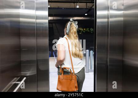 Uscendo dall'ascensore, donna con la borsetta che entra in un moderno edificio per uffici Foto Stock