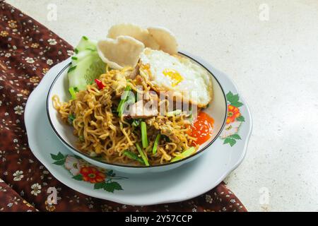 Spaghetti fritti su un piatto bianco rotondo con un panno marrone su un tavolo di marmo bianco, cibo indonesiano, spazio negativo Foto Stock