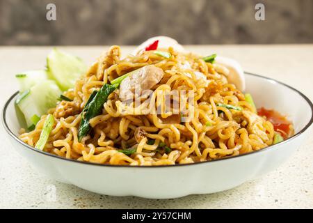 Vista frontale degli spaghetti fritti da vicino con condimento a base di polpette, uova fritte, cibo indonesiano fatto in casa Foto Stock