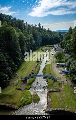 Vista sul lato orientale da una diga di pietra sul fiume Wilczka, fino a un serbatoio vuoto di controllo delle inondazioni a Miedzygorze, Polonia. Foto Stock