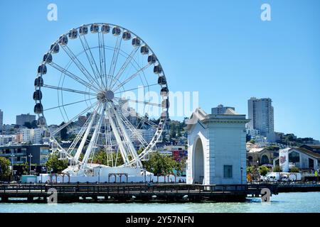 La ruota panoramica SkyStar al Fisherman's Wharf con il Ferry Arch e lo skyline della città. Foto Stock