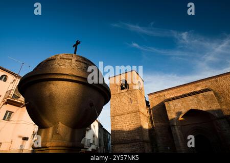 Una fontana a forma di globo sorge in Plaza de San Nicolás con la chiesa dietro di essa sotto un cielo azzurro a Plasencia. Foto Stock