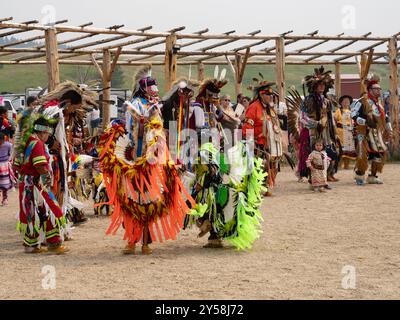 Un gruppo di uomini, donne e bambini nativi americani vestiti in regalia che ballano a un powwow a Lodgepole, Montana. Foto Stock