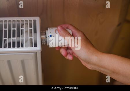 Primo piano sulla mano di una donna che regola la valvola del termostato in una casa di legno. Foto di alta qualità Foto Stock