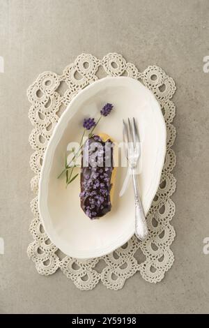 Eclair con glassa al cioccolato con frutta candita topping di lavanda Foto Stock